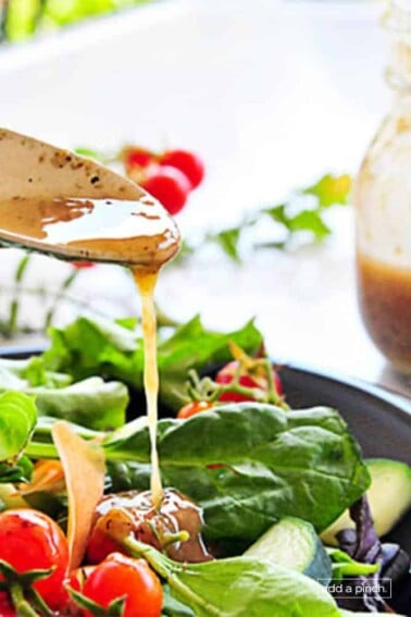 Image of buttermilk dressing being spooned onto a plate of green salad with tomatoes, cheese, and avocado.