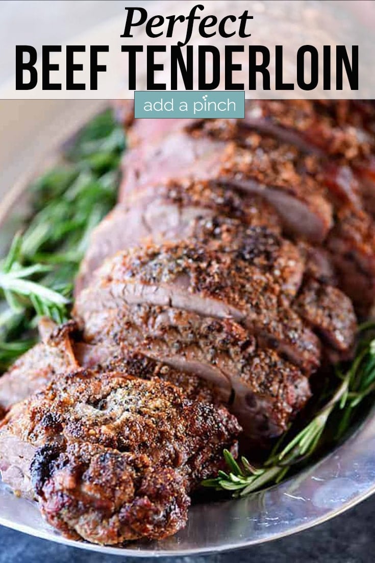 Sliced Beef Tenderloin on platter surrounding by herbs - with text -addapinch.com