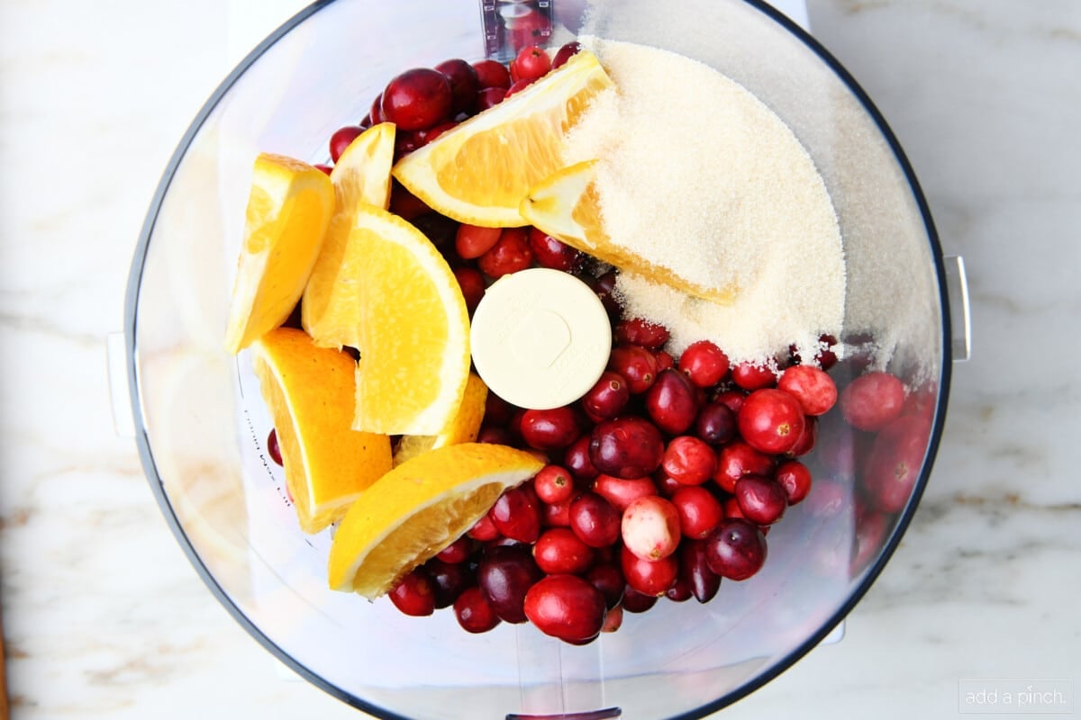 Fresh cranberries, orange slices, and sugar in a food processor.