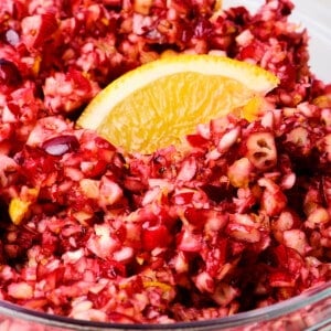 Cranberry relish in a glass bowl with an orange slice for garnish.