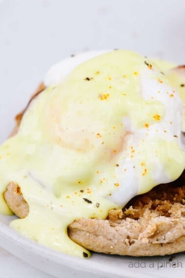 Eggs Benedict Recipe - Toasted English muffins topped with ham, bacon, or Canadian-style bacon, and poached eggs and then drizzled with hollandaise sauce make this a favorite brunch recipe. // addapinch.com