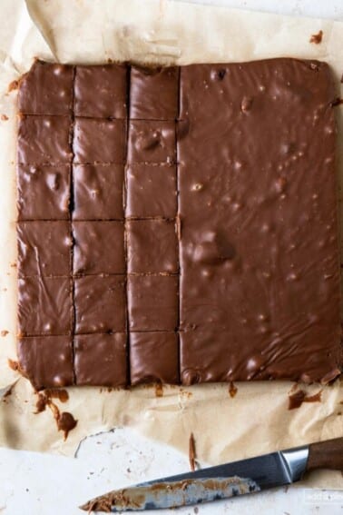 Photo of block of fudge being cut into individual pieces on a parchment