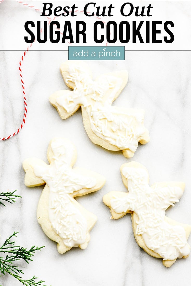 Three angel shaped Cut Out Sugar Cookies on marble background with holiday greenery - with text - addapinch.com