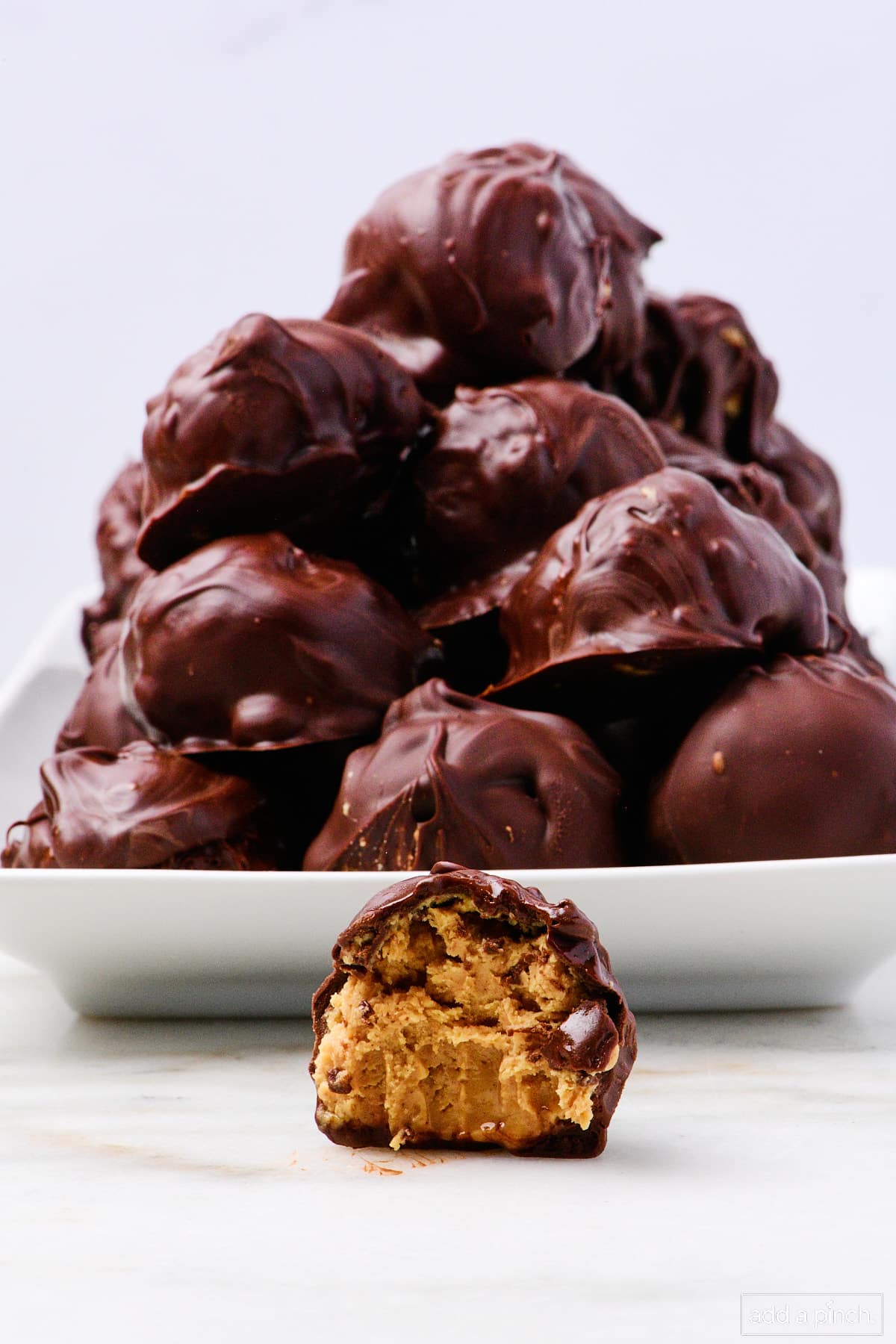 Stack of peanut butter balls on a serving platter with one in front with a bite out of it. 