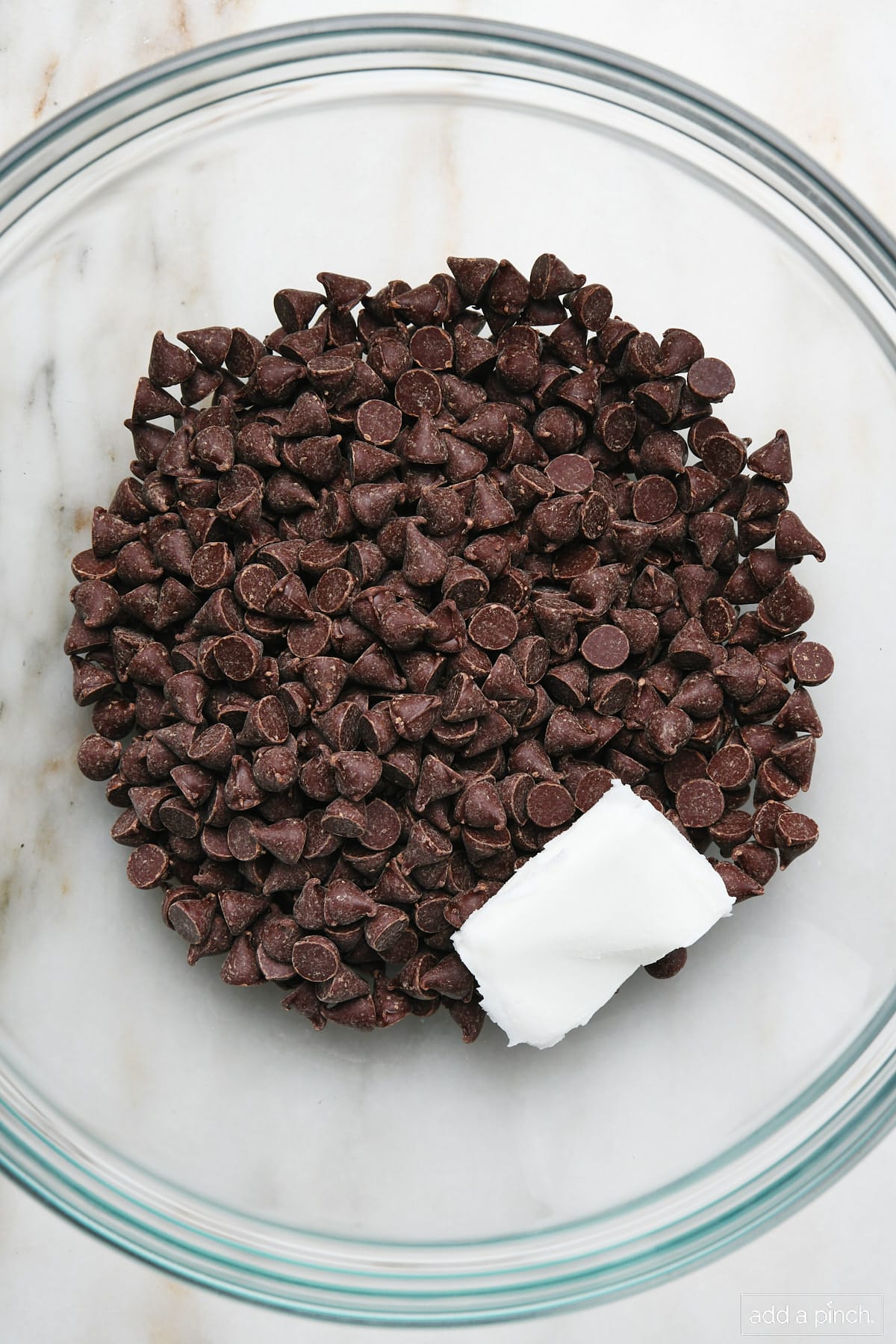 Chocolate chips and shortening in a glass bowl.