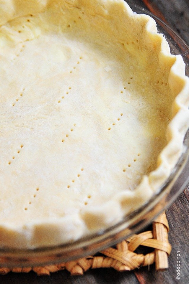 Unbaked pie crust is laid into a pie plate. Fluted around the edges with fork pricks dotted through the bottom  // addapinch.com