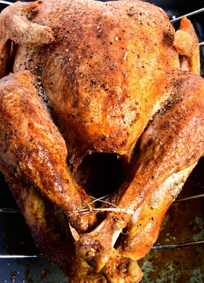 Photo of a roasted turkey on a roasting pan simply seasoned with butter, salt and pepper. 