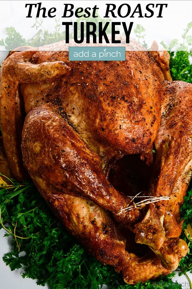 Golden brown Roast Turkey on platter with green herbs - with text - addapinch.com