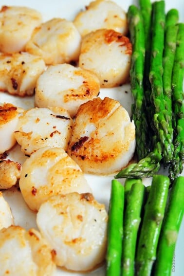 Seared scallops and asparagus on a white platter. // addapinch.com