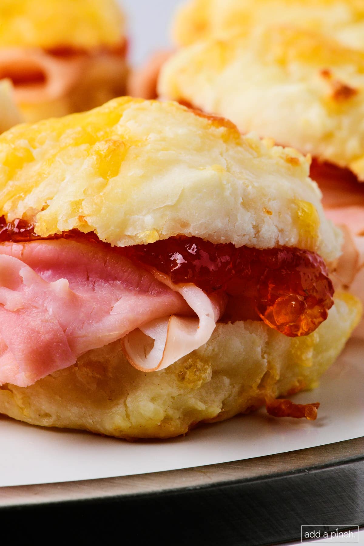 Southern ham biscuits with pepper jelly on a white platter.