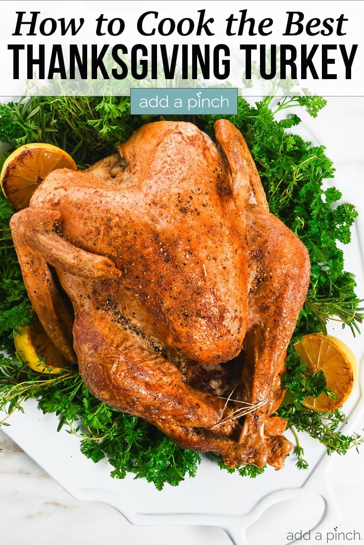 Roast Turkey on platter adorned with green herbs and roasted lemons - with text - addapinch.com